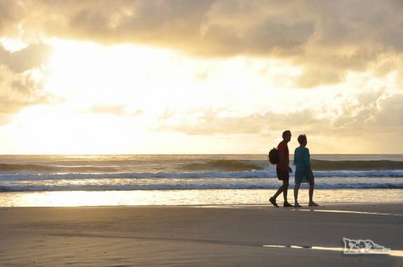 O Rodrigo e sua mãe caminham na praia enquanto o dia nasce em Punta del Diablo, no litoral do Uruguai